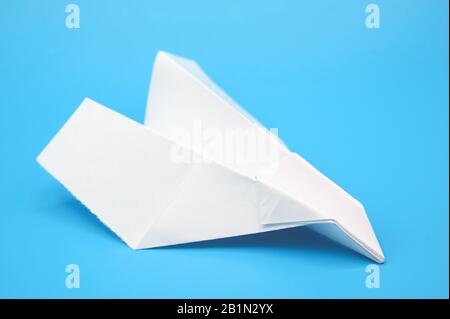 White paper plane on blue background . Stock Photo