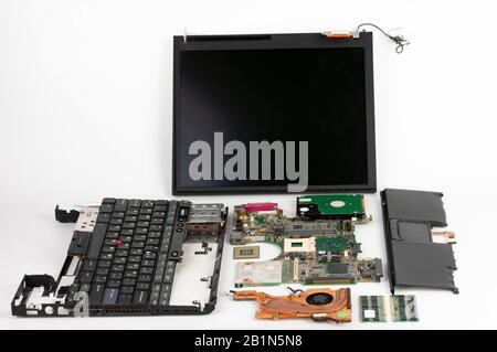 Disassembled laptop, basic components of notebook, screen, keyboard, processor, motherboard, internal  hard disk drive, CPU fan. Stock Photo