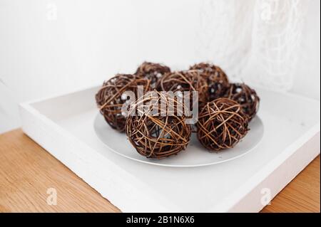 Decorated circles woven from branches, nests on a white plate in the interior. Accessories for a BOHO-style room Stock Photo