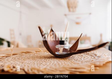 Aroma diffuser with chopsticks in the skin of a nut on a wicker Salomon napkin. Items for Spa and aromatherapy in the Balinese interior boho style Stock Photo