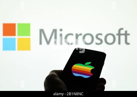 Apple company logo seen displayed on smart phone screen with Microsoft logo visible blurred in the background Stock Photo