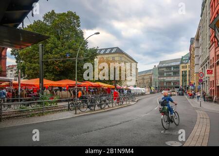A woman rides a bicycles down a busy street past the Hackescher Markt square in the Mitte district of Berlin Germany Stock Photo