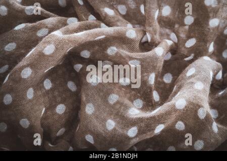 Detail of a crumpled shawl in brown color with white polka dots Stock Photo
