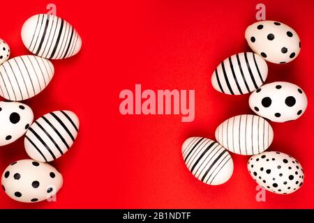 Different graphic hand-painted eggs on bright red background. Easter concept. Place for text. Stock Photo