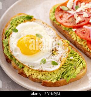 Avocado toasts with fried egg and heirloom tomatoes Stock Photo