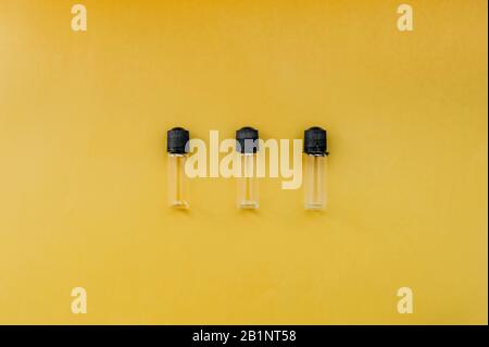 three small empty transparent jar with a black lid for cosmetology or medicine on a uniform bright yellow background Stock Photo