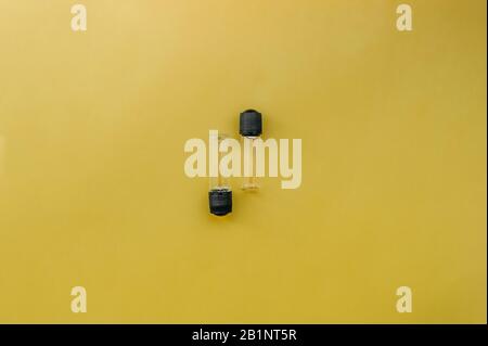 two small empty transparent jar with a black lid for cosmetology or medicine on a uniform bright yellow background Stock Photo