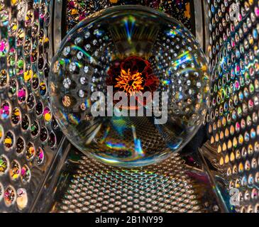 A marigold trapped in a glass globe, which is also trapped inside a cage Stock Photo