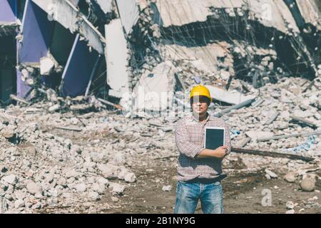 Engineer holding tablet is checking for destruction, demolishing building. Stock Photo