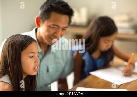 Mother Helping Her Daughters With Their Homework Stock Photo
