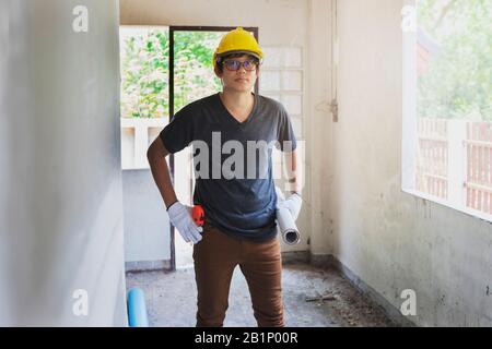 Engineer or Architect holding blueprint and helmet in building construction site. Stock Photo