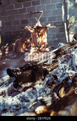 Traditional suckling pig cooked on the charcoal grill. The little pig is roasted whole on an open fire. Organic pig on the spit. Stock Photo