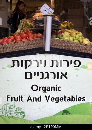 Organic fruit and vegetable stand in Carmel Market (Shuk HaCarmel), the largest market in Tel Aviv, Israel. Sign in English and Hebrew languages. Stock Photo