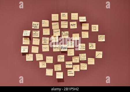 Wine-red wall with hanging yellow sticky notes Stock Photo