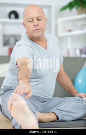 mature man stretching his leg Stock Photo