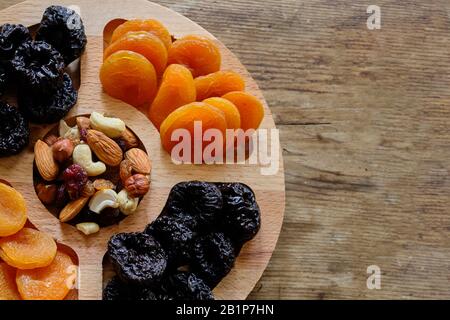 Dried apricots, prunes and nut mix at weathered wooden background. Stock Photo