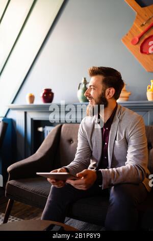 Portrait of handsome businessman smiling while using tablet in office Stock Photo