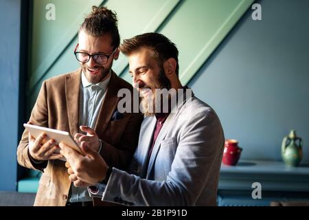Portrait of happy businessmen using digital devices at meeting Stock Photo