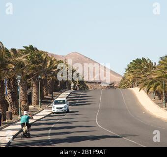 A mobility scooter being ridden by a gentleman on the road in Lanzarote Canary Islands Spain Stock Photo