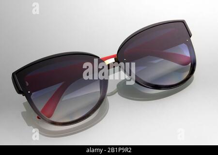 Sunglasses on a background of gray gradient with shadow reflection. Black glasses with red ears. Stock Photo