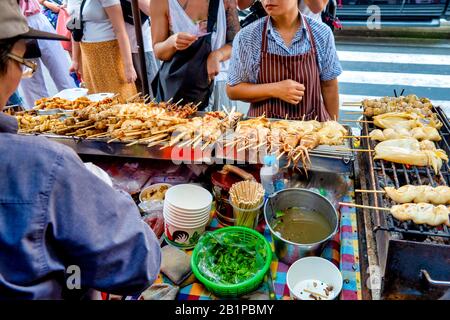 Woman selling Plaa Mhuk Yang (grilled squid) on Thanon Yaowarat, Bangkok Stock Photo