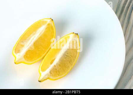 two fresh lemon slices on white plate on wood table. Stock Photo