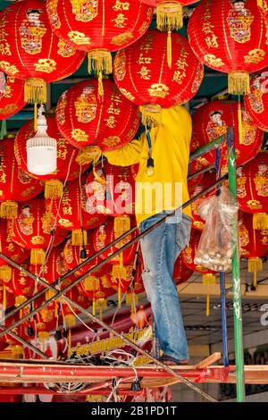 A man setting up lanterns for Chinese New Year in Wat Mangkon Kamalawat temple in Chinatown, Bangkok, Thailand Stock Photo