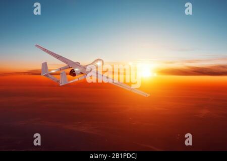 unmanned military aircraft in the evening sky flies to the horizon Stock Photo