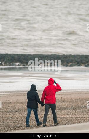 27 February 2020, Lower Saxony, Norderney: A winterly dressed couple goes for a walk on the North Sea beach of Norderney in the morning when it is cold. Photo: Mohssen Assanimoghaddam/dpa Stock Photo