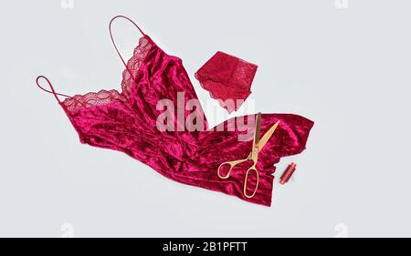 Work table of a tailor. Velvet dress, scissors, lace on a gray background. Flat lay. Copy space. Top view. Stock Photo