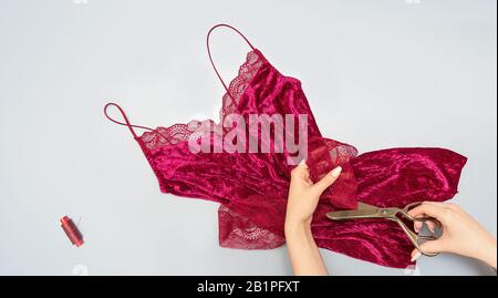 The process of manually sewing linen. Scissors, accessories for sewing. Hands of a tailor close up. Flat lay. Copy space. Stock Photo