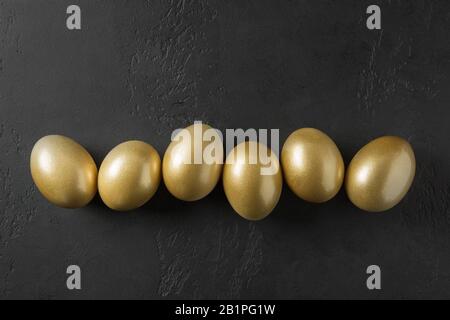 Chicken colored golden eggs on black. Easter dark concept. View from above. Easter composition. Spring. Stock Photo