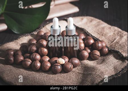 Macadamia oil in bottles and macadamia nuts ,  vintage rustic style .  Bio, organic , nature cosmetics concept Stock Photo