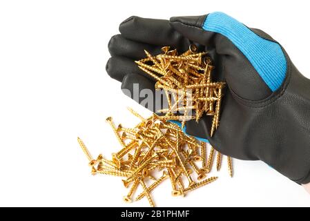 A male hand in a glove spills out yellow zinc torx screws. Stock Photo
