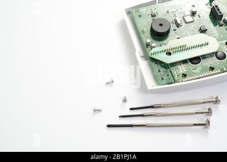 Home alarm control panel repairing. Open Electronic board panel with screwdrivers on a white background. Stock Photo