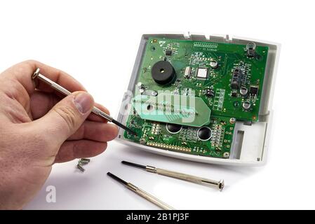 Home alarm control panel repairing. Open Electronic board panel with screwdrivers on a white background. Stock Photo