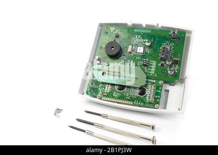 Home alarm control panel repairing. Open Electronic board panel with screwdrivers on a white background. Stock Photo