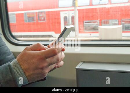 close up man's hands using cellphone at train Stock Photo