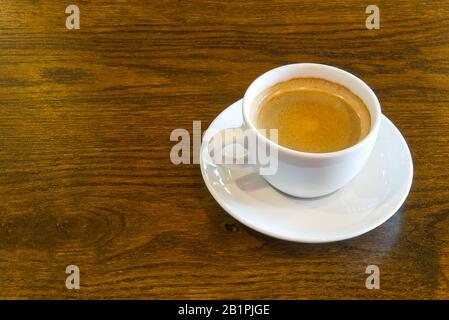 Cup of coffee on wooden table in restoran or coffee house. White ceramic cup view above with copy space Stock Photo