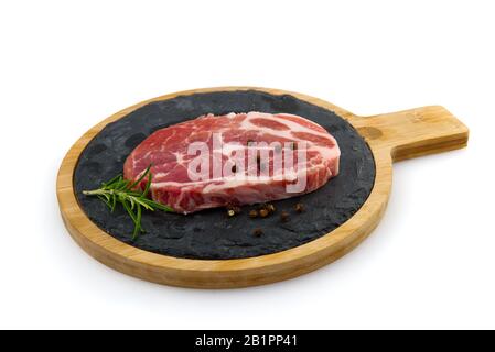 single raw pork slic on black stone plate, isolated on white. Stock Photo