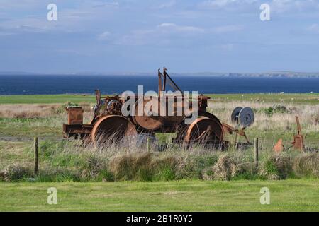 Road roller returning to nature in the far North East of Scotland, with Orkney Islands in the background. Stock Photo