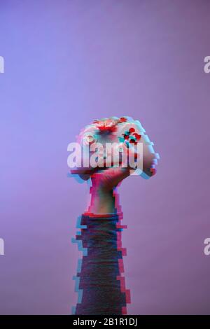 Hand with white gamepad on violet background. Gamer concept. Image with glitch effect. Stock Photo