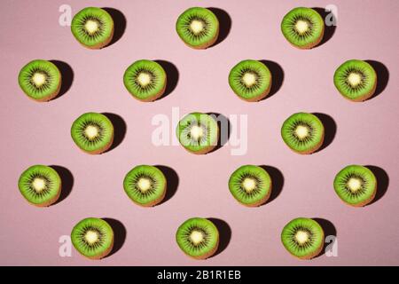 Kiwi fruits elements pattern layout, minimalist abstract design flat lay, healthy food, angle view, pastel pink background Stock Photo