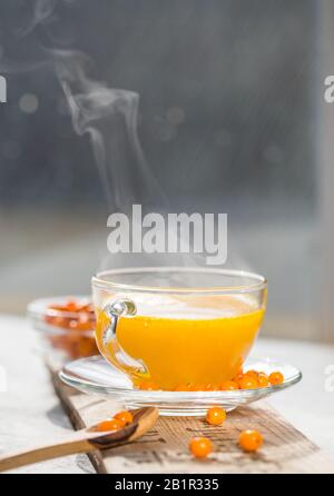 Sea buckthorn tea  in a glass cup before window.   Herbal vitamin beverage Stock Photo