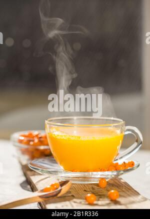 Sea buckthorn tea  in a glass cup before window.   Herbal vitamin beverage Stock Photo