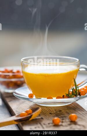 Sea buckthorn tea  in a glass cup before window.   Herbal vitamin beverage Stock Photo