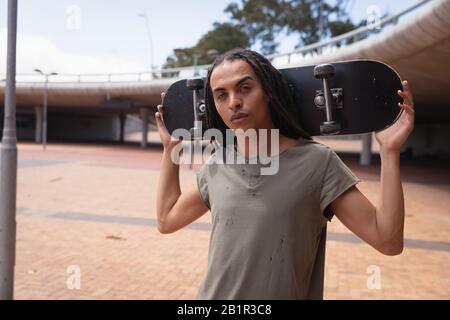 Mixed race man carrying a skateboard Stock Photo