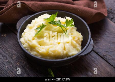 Mashed potatoes, boiled puree in cast iron pot on dark wooden rustic background, top view Stock Photo
