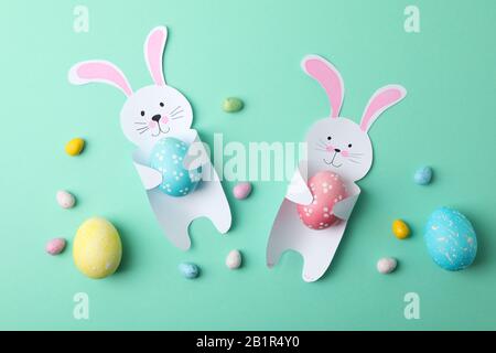 Decorative bunnies and Easter eggs on mint background, top view Stock Photo