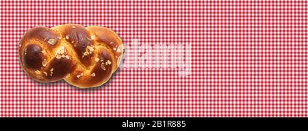 Sweet bread, easter tsoureki, cozonac on red checkered tablecloth background. Braided brioche, festive traditional challah. Banner, copy space Stock Photo
